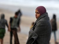 A displaced Palestinian woman stands outside her tent, which is damaged by wind and rain following heavy rainfall in Deir al-Balah, central...