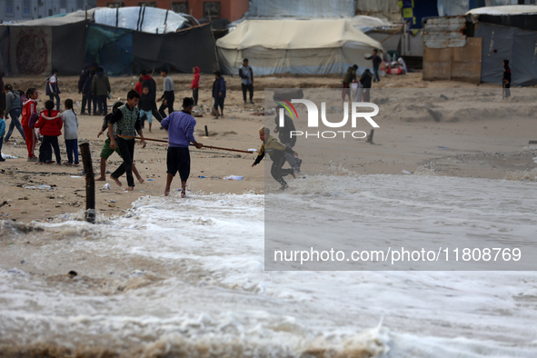 Displaced Palestinian boys walk along the seashore outside their tents, which are damaged by wind and rain following heavy rainfall in Deir...