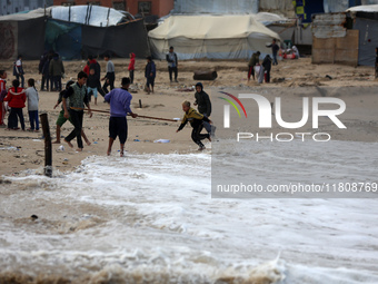 Displaced Palestinian boys walk along the seashore outside their tents, which are damaged by wind and rain following heavy rainfall in Deir...