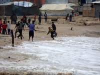 Displaced Palestinian boys walk along the seashore outside their tents, which are damaged by wind and rain following heavy rainfall in Deir...