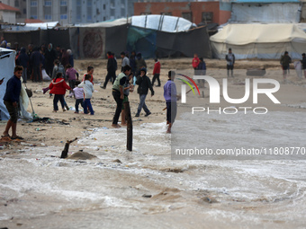 Displaced Palestinian boys walk along the seashore outside their tents, which are damaged by wind and rain following heavy rainfall in Deir...