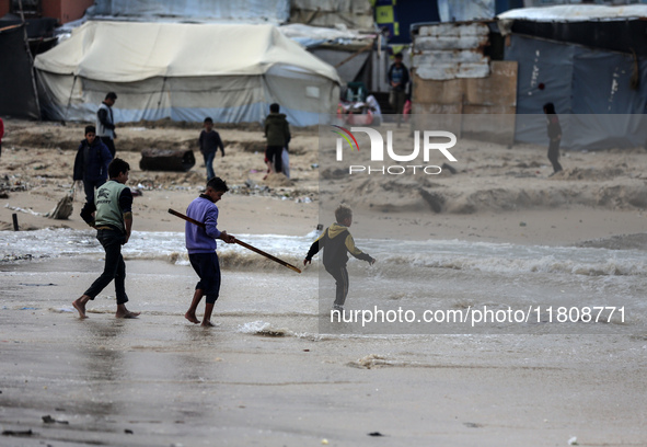 Displaced Palestinian boys walk along the seashore outside their tents, which are damaged by wind and rain following heavy rainfall in Deir...