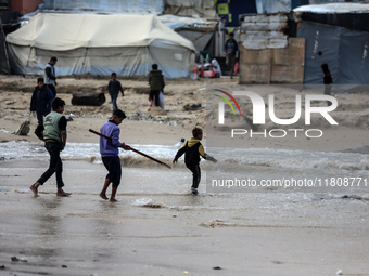 Displaced Palestinian boys walk along the seashore outside their tents, which are damaged by wind and rain following heavy rainfall in Deir...