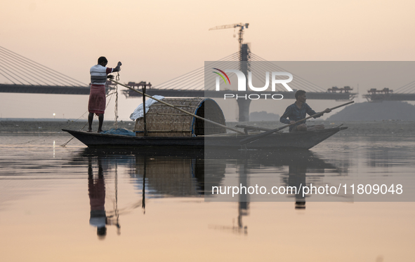 Fishermen lay their fishing net in the Brahmaputra River during sunset in Guwahati, India, on November 25, 2024. 