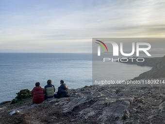 Three men look at the lighthouse on the Howth Cliff Walk in Howth, Ireland, in November 2024 (