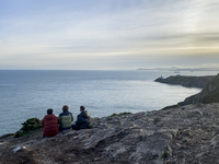 Three men look at the lighthouse on the Howth Cliff Walk in Howth, Ireland, in November 2024 (