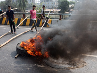 Students of Dr. Mahbubur Rahman Molla College set fire to a tire before they engage in a clash with students from Kabi Nazrul College and Su...