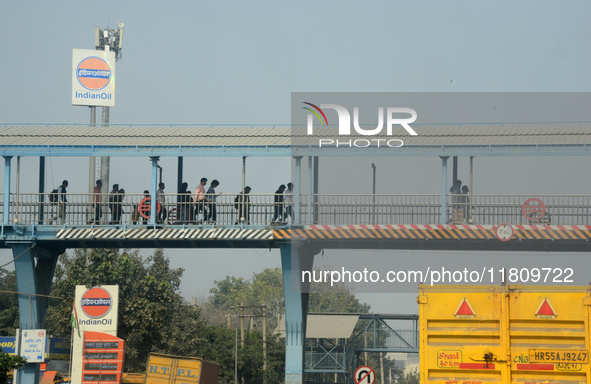 People walk on the foot over bridge during smoggy conditions in New Delhi, India, on November 24, 2024. 