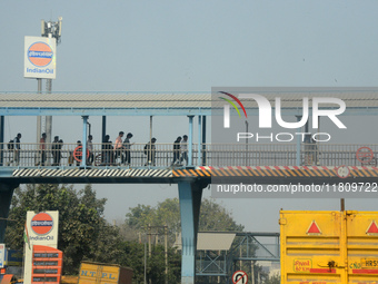 People walk on the foot over bridge during smoggy conditions in New Delhi, India, on November 24, 2024. (