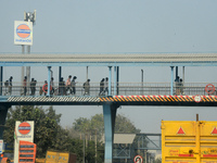 People walk on the foot over bridge during smoggy conditions in New Delhi, India, on November 24, 2024. (