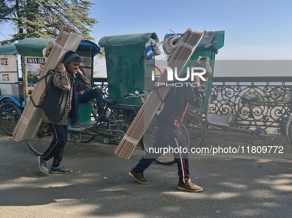 Laborers carry planks of wood along the Mall Road in Mussoorie, Uttarakhand, India, on April 18, 2024. 