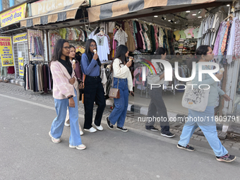 Indian tourists eat ice cream while walking along the Mall Road in Mussoorie, Uttarakhand, India, on April 18, 2024. (