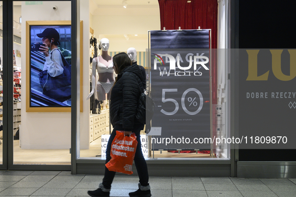 A person walks past a shop with Black Week advertisements during Black Friday week in Warsaw, Poland, on November 25, 2024. 