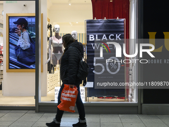 A person walks past a shop with Black Week advertisements during Black Friday week in Warsaw, Poland, on November 25, 2024. (