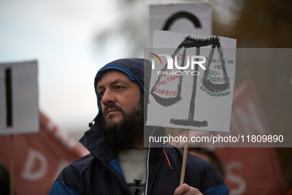 A protester holds a placard depicting Justice's scale with 'Corporate, politicians, lobbies' on one side and 'Environment, biodiversity, qua...