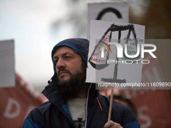 A protester holds a placard depicting Justice's scale with 'Corporate, politicians, lobbies' on one side and 'Environment, biodiversity, qua...