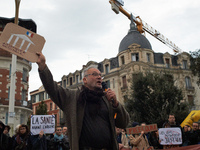 An opponent speaks with a placard depicting the French National Assembly. People gather in Toulouse, France, on November 25, 2024, as plaint...