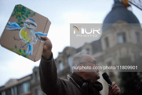 An opponent holds a cardboard sign with a message. People gather in Toulouse, France, on November 25, 2024, as plaintiffs, including LVEL, A...