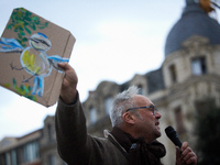 An opponent holds a cardboard sign with a message. People gather in Toulouse, France, on November 25, 2024, as plaintiffs, including LVEL, A...