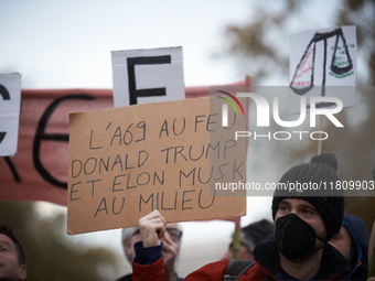 A man holds a placard reading 'A69 in the fire, Donald Trump and Elon Musk in the middle'. People gather in Toulouse, France, on November 25...