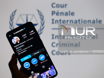 Benjamin Netanyahu's social media is displayed on a smartphone with the International Criminal Court logo visible in the background in this...