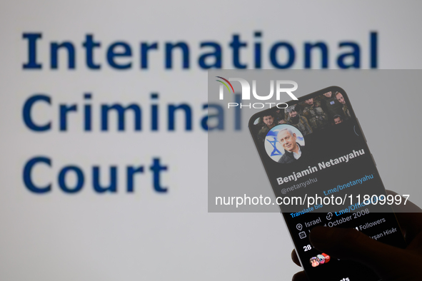 Benjamin Netanyahu's social media is displayed on a smartphone with the International Criminal Court visible in the background in this photo...