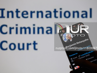 Benjamin Netanyahu's social media is displayed on a smartphone with the International Criminal Court visible in the background in this photo...