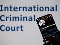 Benjamin Netanyahu's social media is displayed on a smartphone with the International Criminal Court visible in the background in this photo...