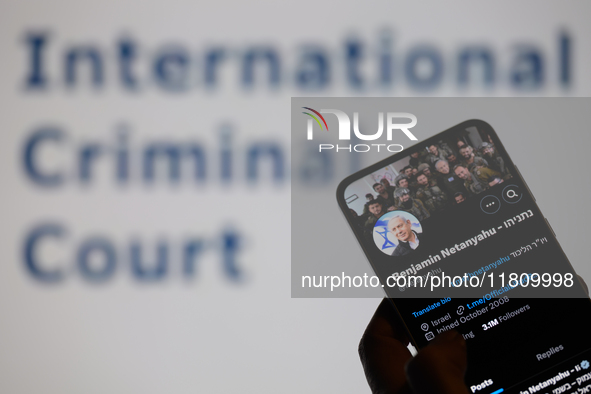 Benjamin Netanyahu's social media is displayed on a smartphone with the International Criminal Court visible in the background in this photo...