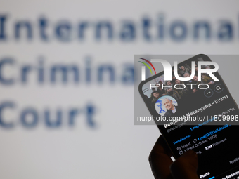 Benjamin Netanyahu's social media is displayed on a smartphone with the International Criminal Court visible in the background in this photo...