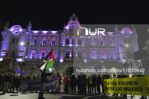 Demonstrators carry signs saying no more violence against women and a Palestinian flag as they walk past the town hall, which is lit up in p...