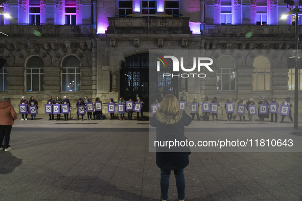 Demonstrators with signs reading ''They are not dead, they are murdered'' pose in front of the town hall illuminated in purple for the demon...