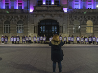 Demonstrators with signs reading ''They are not dead, they are murdered'' pose in front of the town hall illuminated in purple for the demon...