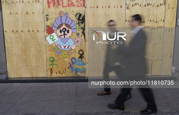 Pedestrians cross the street in front of a mural in the Zocalo of Mexico City, Mexico, on November 25, 2024, coinciding with the Internation...