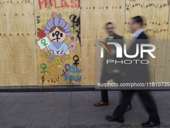 Pedestrians cross the street in front of a mural in the Zocalo of Mexico City, Mexico, on November 25, 2024, coinciding with the Internation...