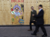 Pedestrians cross the street in front of a mural in the Zocalo of Mexico City, Mexico, on November 25, 2024, coinciding with the Internation...