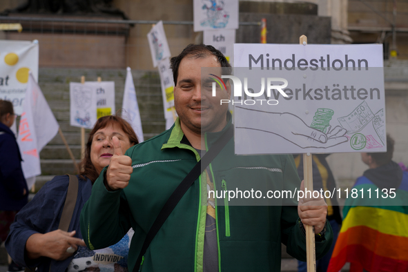 A demonstrator holds a sign reading 'Mindestlohn in Werkstatten' ('Minimum Wage in Workshops') at Odeonsplatz in Munich, Germany, on October...