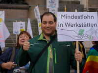 A demonstrator holds a sign reading 'Mindestlohn in Werkstatten' ('Minimum Wage in Workshops') at Odeonsplatz in Munich, Germany, on October...