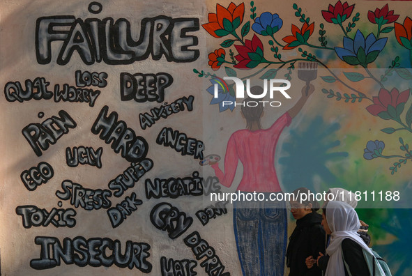 College students walk past graffiti on a wall in Srinagar, Jammu and Kashmir, on November 26, 2024. In total, 11.3% of the adult population...