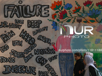 College students walk past graffiti on a wall in Srinagar, Jammu and Kashmir, on November 26, 2024. In total, 11.3% of the adult population...