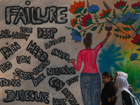 College students walk past graffiti on a wall in Srinagar, Jammu and Kashmir, on November 26, 2024. In total, 11.3% of the adult population...