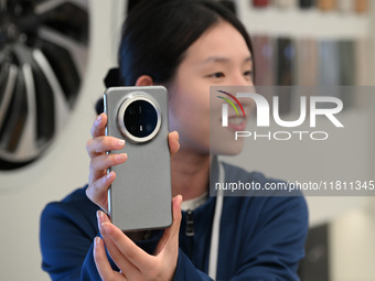 A Huawei employee displays the Mate70 phone in Nanjing, China, on November 26, 2024. (