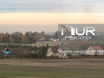 KRAKOW, POLAND - NOVEMBER 19:   
A small village with frozen fields and trees losing their leaves, seen from a train window as winter approa...