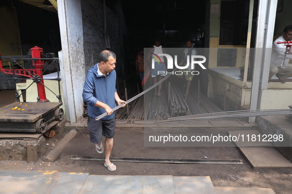 Labourers carry iron rods outside a shop at a steel and iron wholesale market in Kolkata, India, on November 26, 2024. In November 2024, Ind...