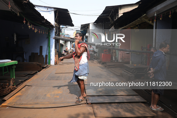 A laborer carries iron rods outside a shop at a steel and iron wholesale market in Kolkata, India, on November 26, 2024. In November 2024, I...