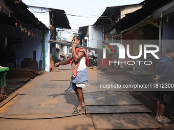 A laborer carries iron rods outside a shop at a steel and iron wholesale market in Kolkata, India, on November 26, 2024. In November 2024, I...