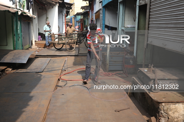 A laborer works with an iron plate outside a shop at a steel and iron wholesale market in Kolkata, India, on November 26, 2024. In November...