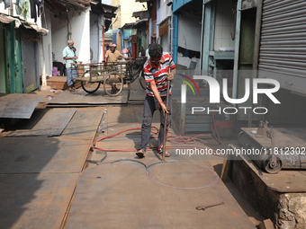 A laborer works with an iron plate outside a shop at a steel and iron wholesale market in Kolkata, India, on November 26, 2024. In November...