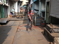 A laborer works with an iron plate outside a shop at a steel and iron wholesale market in Kolkata, India, on November 26, 2024. In November...