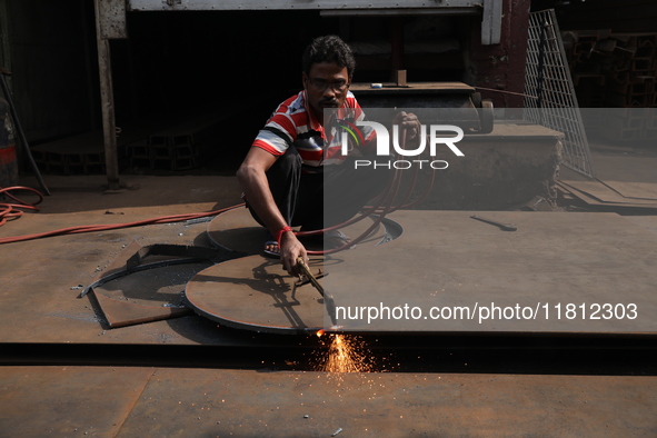 A laborer cuts an iron plate outside a shop at a steel and iron wholesale market in Kolkata, India, on November 26, 2024. In November 2024,...